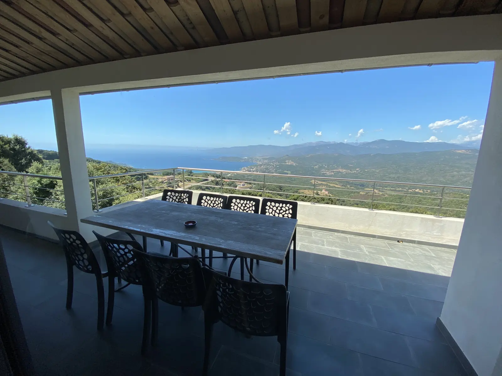 Terrasse couverte avec table et vue mer